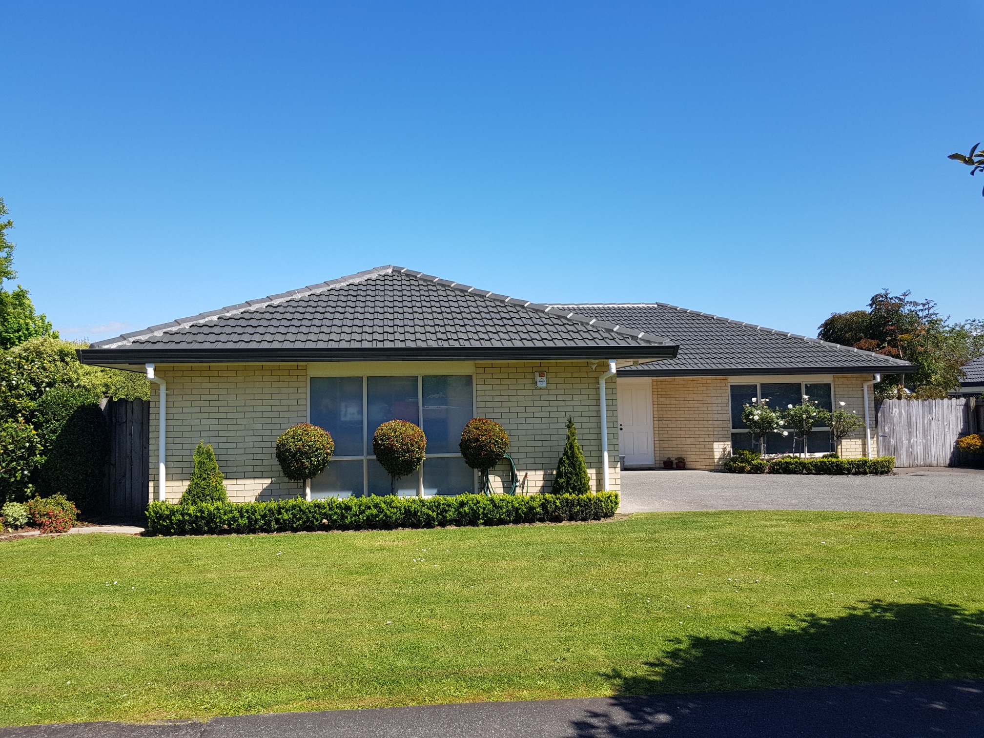 Modern concrete tile roof restoration completed, Coating 1x coat of penetrating tile sealer 1x high build base coat and 1 x Acrylic gloss top coat, Colour Karaka. 15 year warranty